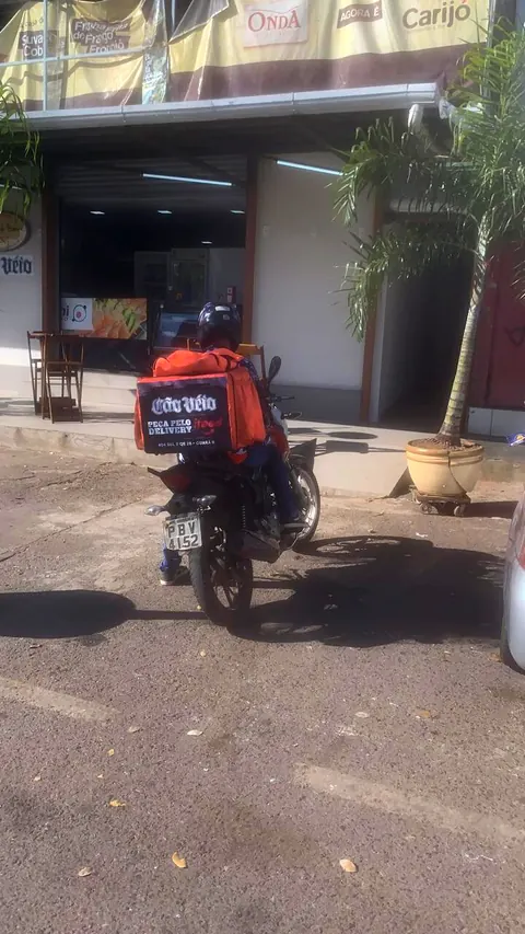 Moto estacionada com a bag adesivada do Cão Véio na garupa